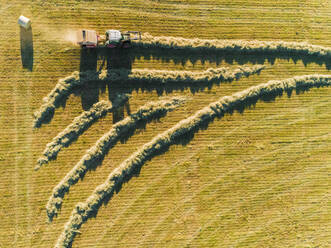 Abstract aerial view of tractor harvesting straw bales in field in Correze, France - AAEF00091
