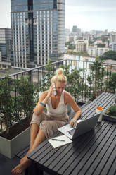 Kaukasische Frau, die auf einem Balkon mit einem Handy telefoniert - BLEF10709