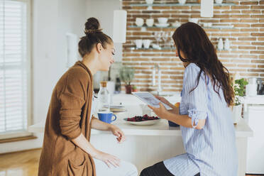 Caucasian women using digital tablet at counter - BLEF10727