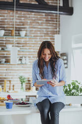 Caucasian woman using digital tablet in kitchen - BLEF10739