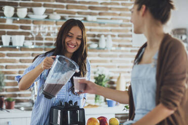 Kaukasische Frauen gießen Smoothie in der Küche - BLEF10749