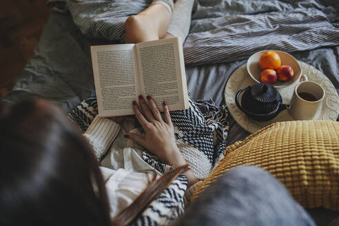 Woman reading book on bed - BLEF10791