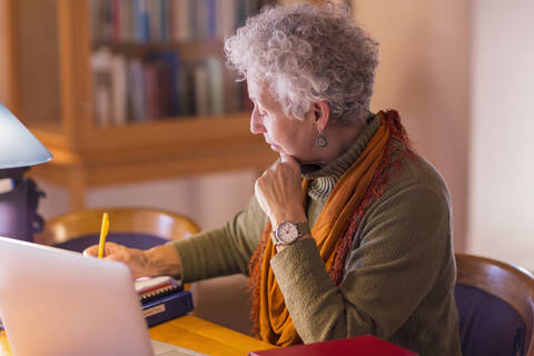 Ältere gemischtrassige Frau schreibt in der Bibliothek, lizenzfreies Stockfoto