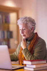 Ältere gemischtrassige Frau benutzt Laptop in der Bibliothek - BLEF10836