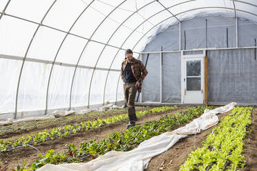 Caucasian farmer walking in greenhouse - BLEF10858
