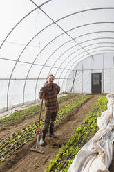 Caucasian farmer standing in greenhouse - BLEF10860