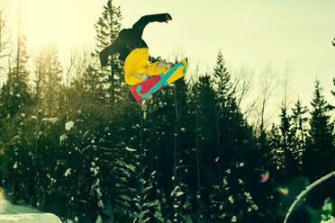Kaukasischer Mann in der Luft auf einem Snowboard - BLEF10906
