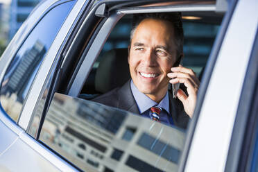 Mixed race businessman talking on cell phone in car - BLEF10954