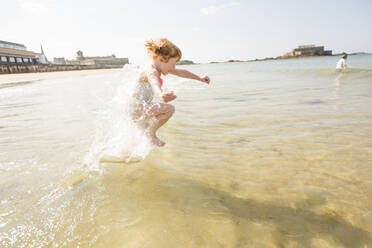 Caucasian girl splashing in waves on beach - BLEF10997