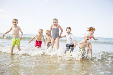 Kaukasische Kinder spielen in den Wellen am Strand - BLEF11000