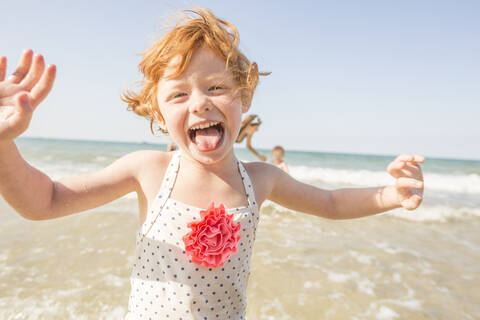 Kaukasisches Mädchen spielt in den Wellen am Strand, lizenzfreies Stockfoto