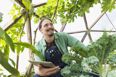 Caucasian gardener using digital tablet in greenhouse - BLEF11018