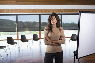 Hispanic businesswoman standing in meeting room - BLEF11046