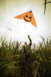 Caucasian couple flying kite in rural field - BLEF11066