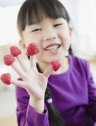 Chinese girl with raspberries on fingers - BLEF11118