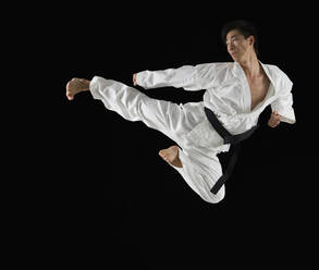 Asian male karate black belt kicking in air - BLEF11136