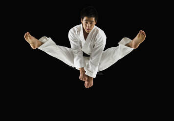 Asian male karate black belt kicking in air - BLEF11137