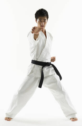 Asiatischer männlicher Schwarzgurt beim Üben von Karate, lizenzfreies Stockfoto