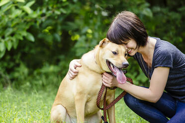 Caucasian woman petting dog in field - BLEF11169