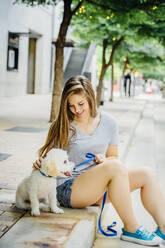 Caucasian woman petting dog on sidewalk - BLEF11177