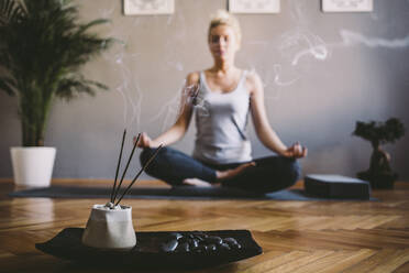 Kaukasische Frau meditiert im Yogastudio - BLEF11220