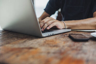 Kaukasischer Mann mit Laptop am Tisch - BLEF11234