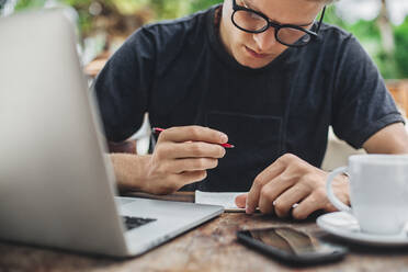 Caucasian man writing in cafe - BLEF11237