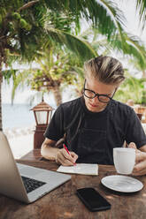 Caucasian man writing in cafe - BLEF11239