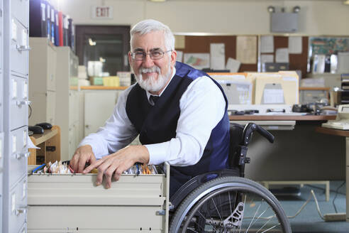 Caucasian businessman filing papers in office - BLEF11317