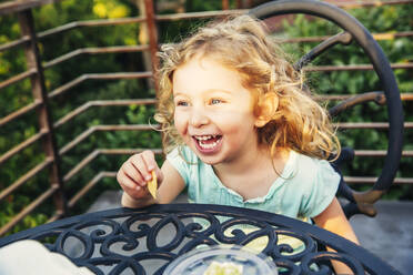 Kaukasisches Mädchen isst auf der Veranda - BLEF11356