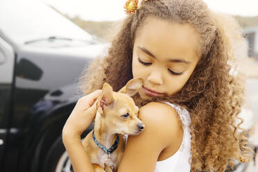 Mixed race girl petting dog outdoors - BLEF11357