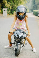 Mixed race girl sitting on miniature motorcycle - BLEF11360