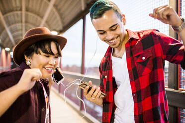 Couple sharing earphones to listen to music - BLEF11366