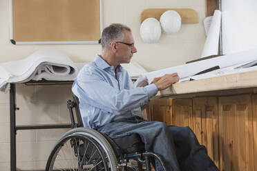 Caucasian architect in wheelchair working in office - BLEF11386