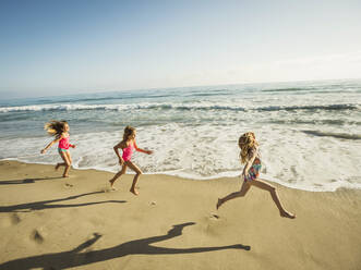 Caucasian sisters running on beach - BLEF11392