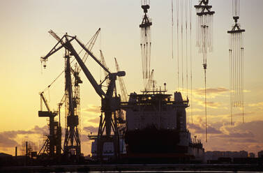 Kräne und ein Tanker in einem Hafen bei Sonnenuntergang - BLEF11408