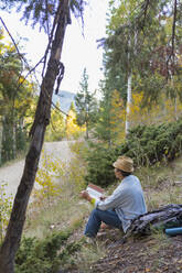 Ein Mann liest ein Buch auf einem ländlichen Hügel - BLEF11421