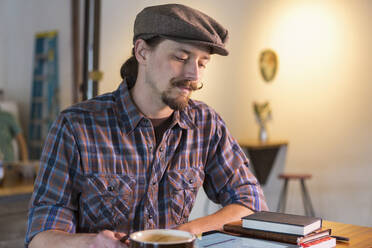 Kaukasischer Mann liest in einem Cafe - BLEF11426