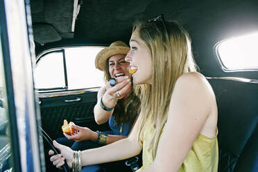 Woman feeding friend in vintage car - BLEF11468