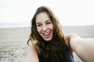 Gemischtrassige Frau macht Selfie am Strand - BLEF11471