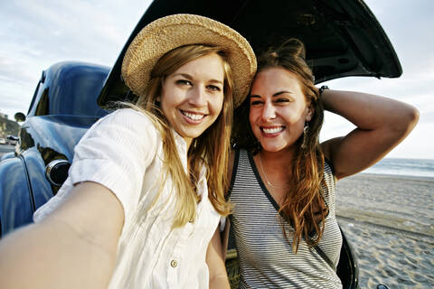 Frauen nehmen Selfie in Oldtimer am Strand, lizenzfreies Stockfoto