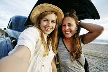 Frauen nehmen Selfie in Oldtimer am Strand - BLEF11476