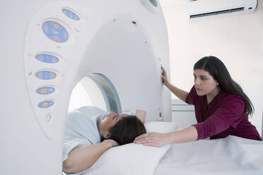 Hispanische Krankenschwester untersucht Patient im MRT-Gerät - BLEF11494