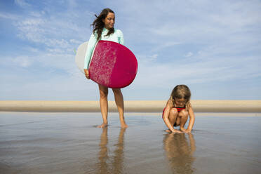 Mutter und Tochter spielen in den Wellen am Strand - BLEF11517