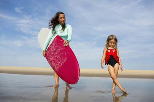 Mother and daughter playing in waves on beach - BLEF11518