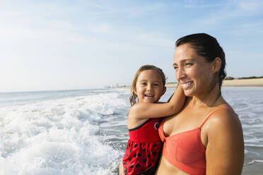 Mother holding daughter on beach - BLEF11523