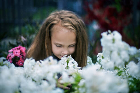Kaukasisches Mädchen riecht an Blumen im Garten - BLEF11536