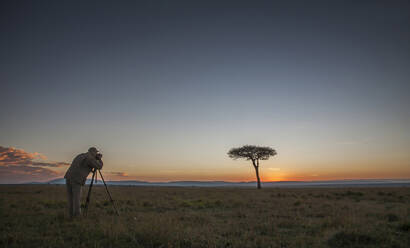 Kaukasischer Fotograf fotografiert Baum in Savanne - BLEF11573