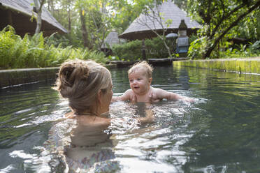 Caucasian mother and baby playing in pool - BLEF11606