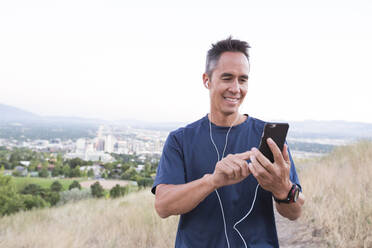 Mixed race man using cell phone on hilltop - BLEF11647